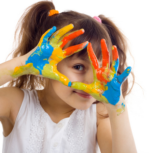 Young girl playing with blue, orange, and yellow paint with hands.