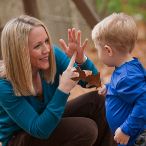 Woman signing the word 'Leaf' in American Sign Language while communicating with her son